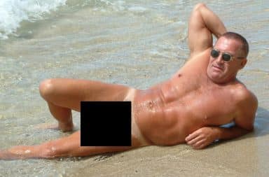 Man sunbathing nude on a beach - penis blacked out