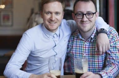 Two men hugging over beers