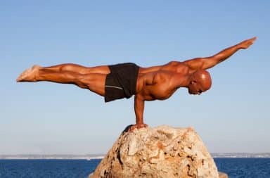 Man balancing horizontally on a rock with one hand