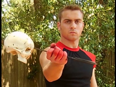 Man holding a knife through a human skull