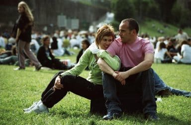 Woman holding onto her boyfriend's leg outside