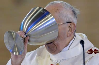 Priest drinking wine out of communion cup