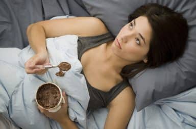 Woman stress eating ice cream in bed