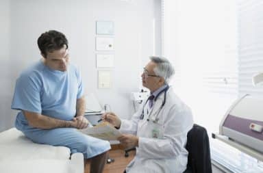 Doctor examining patient's neck in exam room