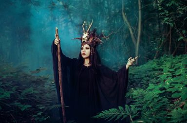 Female witch holding a scepter in the woods