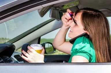 Woman putting on makeup and talking on a cell phone in a self-driving car