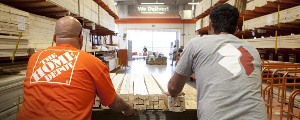 Home Depot employees pushing wood on a cart in the store