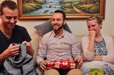 Cousins opening gifts together on the sofa at Christmas