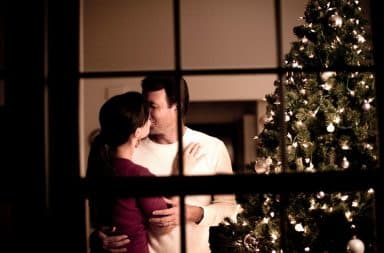 Couple kissing by Christmas tree