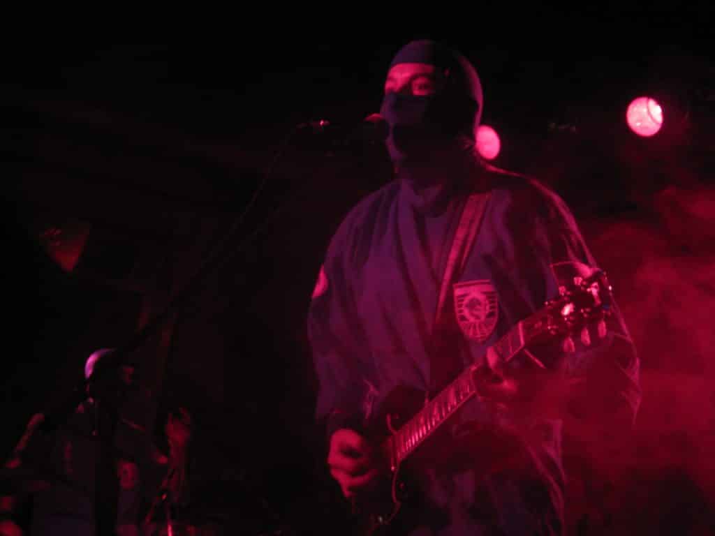 Guy dressed as a ninja playing guitar on stage