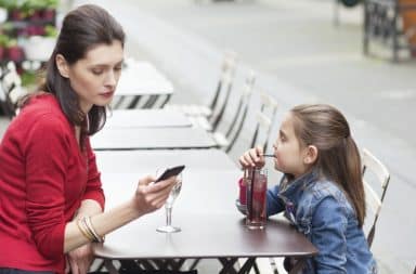 Mom texting with her daughter at a table outside