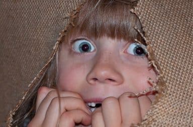 Scared child peeking out of a burlap bag