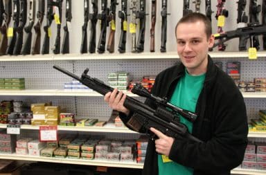 Man holding an automatic rifle in a gun shop at a shopping mall