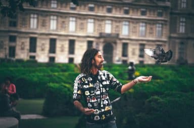 Hippie man feeding pigeon