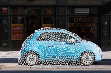 a little blue car caught under a big ol' net