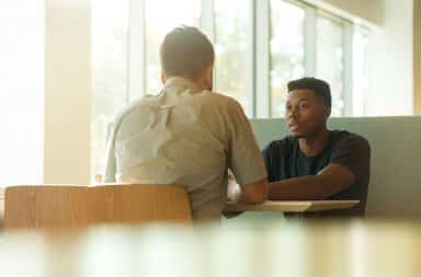 White man interviews black man for a job at a table