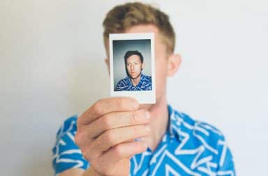 White man holding a photo up of a white man