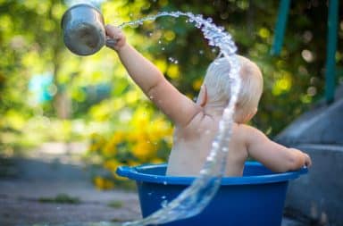 Baby throwing water while taking a bath outside