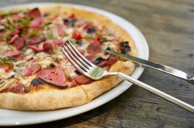 Knife and fork on a plate of pizza