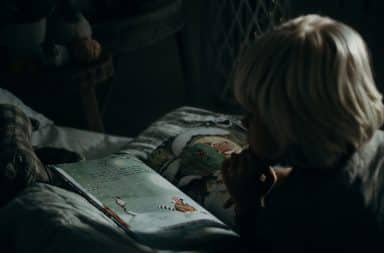 Child reading a book at night in the dark