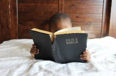 Child reading the Bible in bed