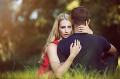 Woman staring inquisitively while hugging a man