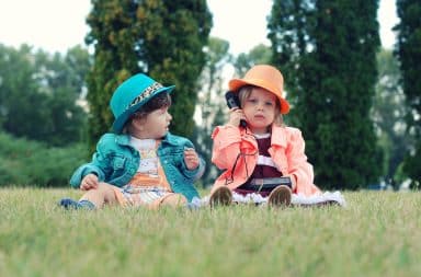 Toddlers sitting on the grass outside talking