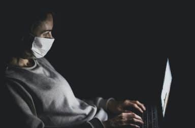 Woman wearing a face mask while typing an email
