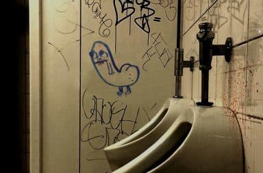 Penis drawings on the wall of a public restroom with urinals