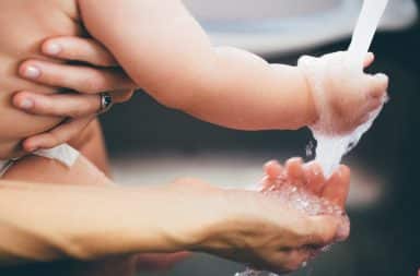 Parent and child washing hands in a sink