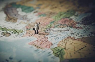 Man waving goodbye standing on a world map