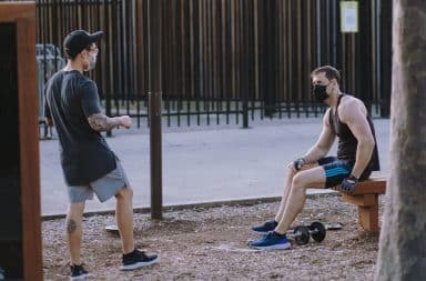 Two men with masks on outside working out