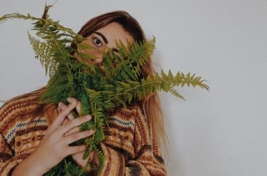 Woman holding a fern and hiding