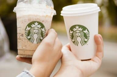 Two Starbucks cups held by a couple