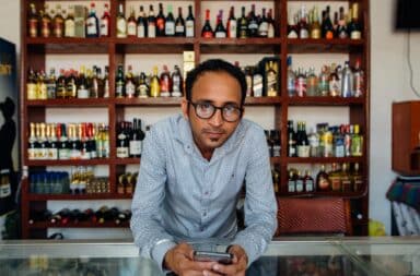 Cashier at a liquor store holding his phone