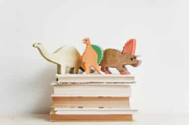 Wooden dinosaurs sitting on a pile of books