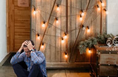 Man sitting down with hands on his head in front of a sliding barn door