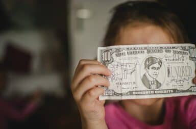 Kid holding up a fake one hundred dollar bill
