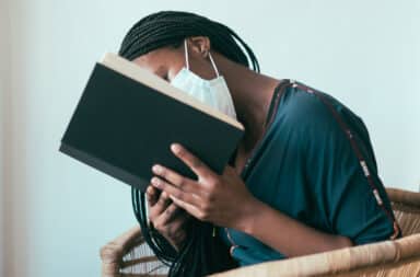 Woman reading a book with face mask on