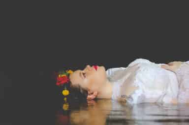 Woman dress in white gown lying down in Shakespeare play