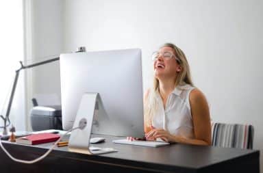 Woman laughing at computer in office