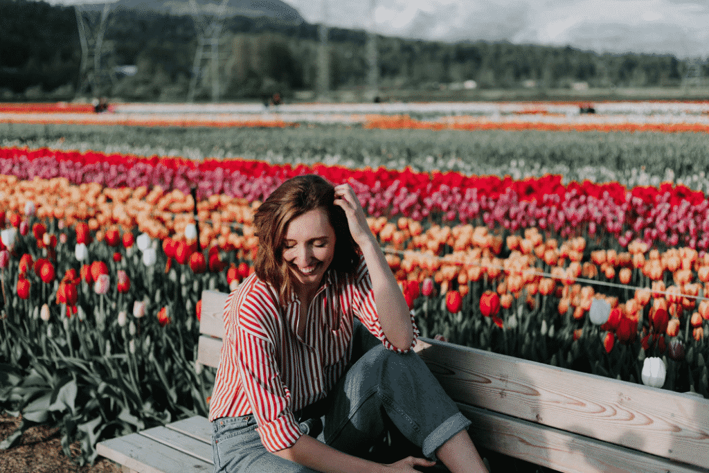 Woman outside on a bench by a flower field