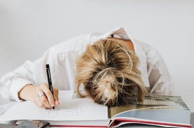 disappointed woman lying with head down on an open book with a pen