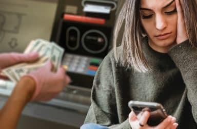 bank ATM money woman is on the phone and it's making her sad