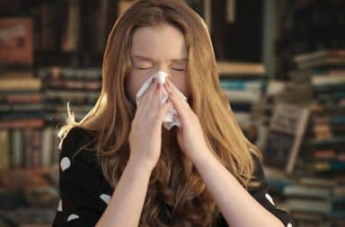 woman sneezing in a bookstore