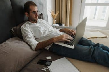 man on bed with computer
