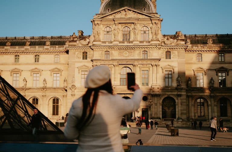 person on phone in front of Louvre
